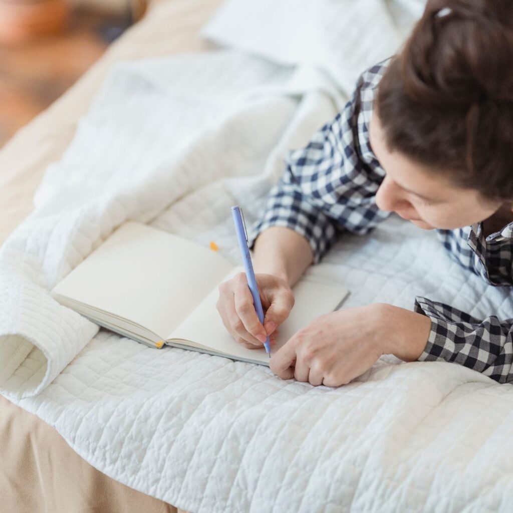 Frau schreibt im Bett in ihr Journal