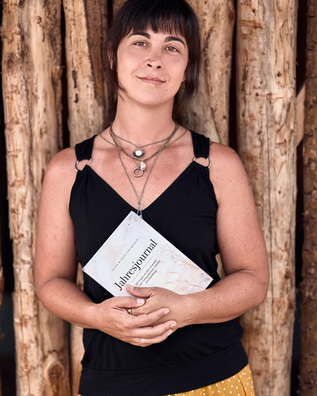 Daniela, Gründerin von Lune & Leaf, hält das Jahresjournal vor einer Holzwand